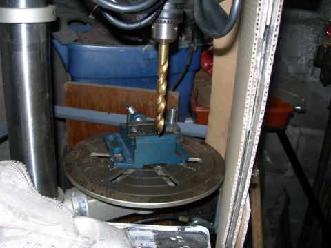 1992 Ford Taurus - A close-up view of a drill press with a metal vise holding a workpiece, set against a backdrop of various workshop items.