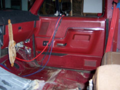 1991 Ford Bronco - Interior of a 1991 Ford Bronco with exposed wiring and red door panels.
