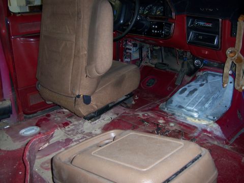 1991 Ford Bronco - The interior of a vehicle, red panels, a brown seat, and a visible dashboard, appears to be undergoing some form of modification or repair.