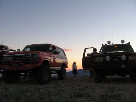 1996 Ford Bronco - Two Ford Broncos are parked on a grassy hill as the sun sets in the background.