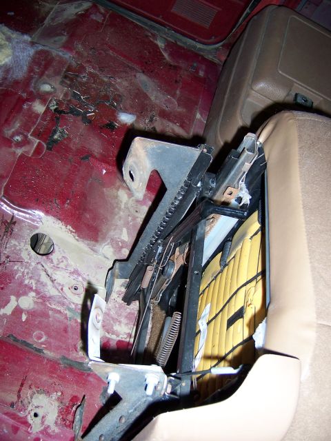 1991 Ford Bronco - Close-up of a car's interior showing exposed seat mounting hardware and a red floor.