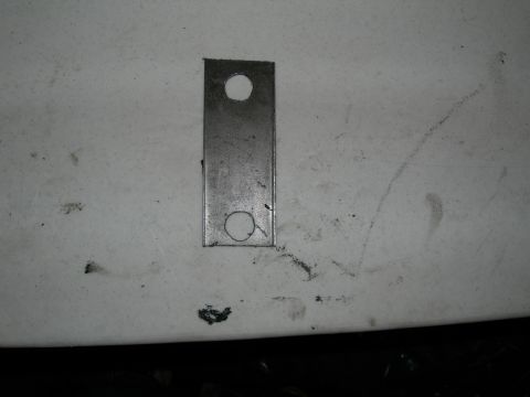1992 Ford Taurus - A close-up view of a metal bracket with two holes, likely a car part.