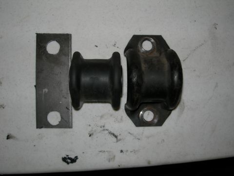 1992 Ford Taurus - Close-up of automotive suspension bushings and a metal bracket on a white surface.
