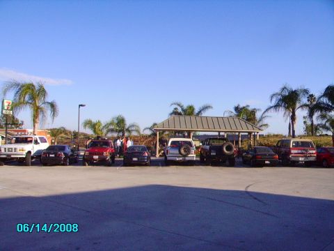 1990 Ford Bronco - Several vehicles, including a 1990 Ford Bronco, are parked outside a 7-Eleven store on a sunny day.