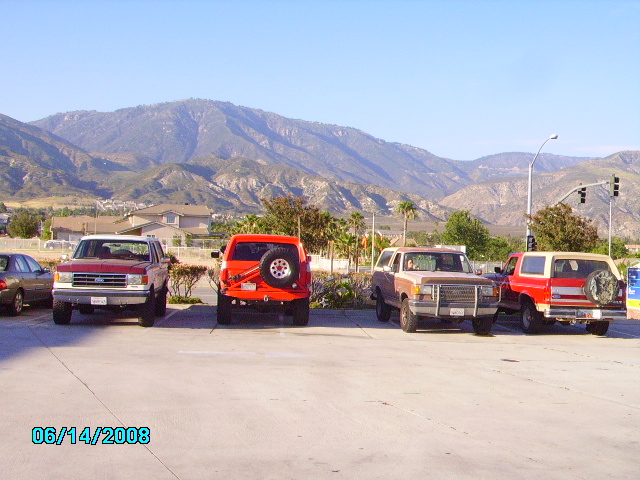 Four Ford Bronco SUVs parked in a lot with mountains in the background