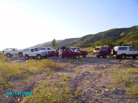 1990 Ford Bronco - A group of SUVs, including Ford Broncos, are parked together in a scenic outdoor location.