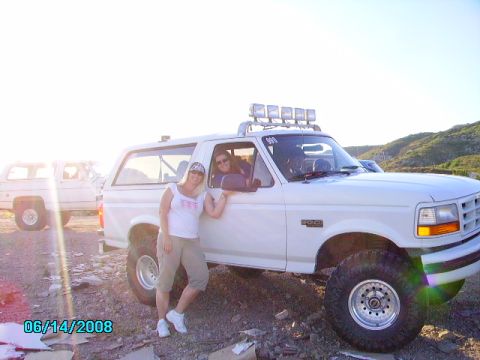1990 Ford Bronco - Two women pose with a lifted white Ford Bronco in a sunny, outdoor setting.