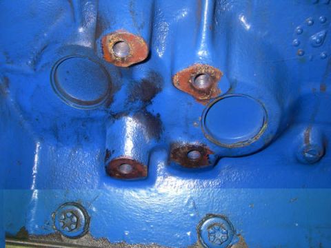 1968 Ford Mustang - A close-up view of a blue engine block shows several bolt holes and circular openings, with some signs of rust.