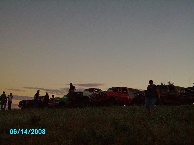 Several SUVs and trucks are parked on a grassy hill during sunset. A date stamp reads 06/14/2008