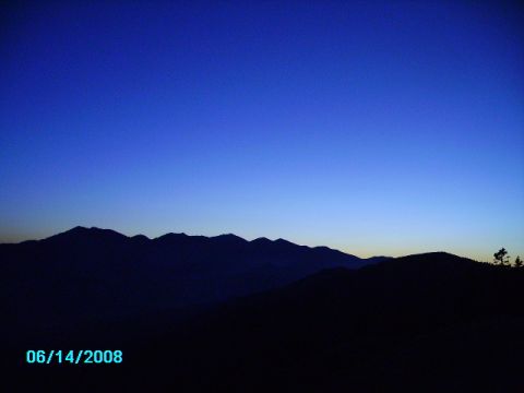 1990 Ford Bronco - A vast mountain range is silhouetted against the twilight sky, with a date and website watermark visible.