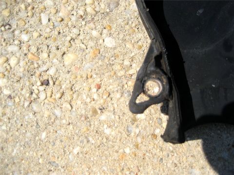 1993 Ford Probe - Close-up of a black plastic automotive part a metal grommet, resting on a gravel surface.
