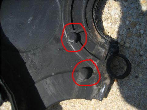 1993 Ford Probe - This is a close-up view of a vehicle's engine timing belt cover, showing two mounting points highlighted with red circles.
