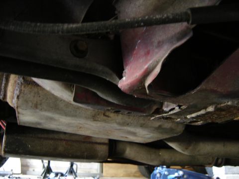 1988 Ford Bronco - Undercarriage view of a red vehicle with visible rust and exhaust system components.