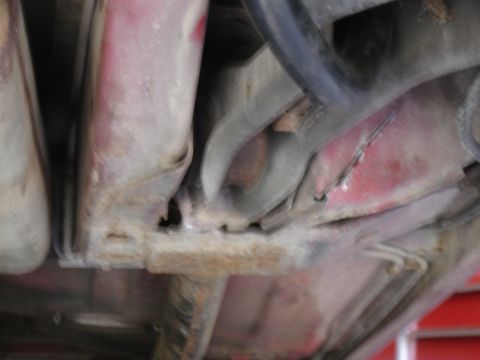 1988 Ford Bronco - Close-up of the undercarriage, showing structural elements and some red paint on the body.