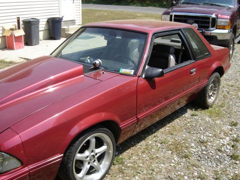 1988 Ford Bronco - Red coupe with a large hood scoop parked next to a truck.