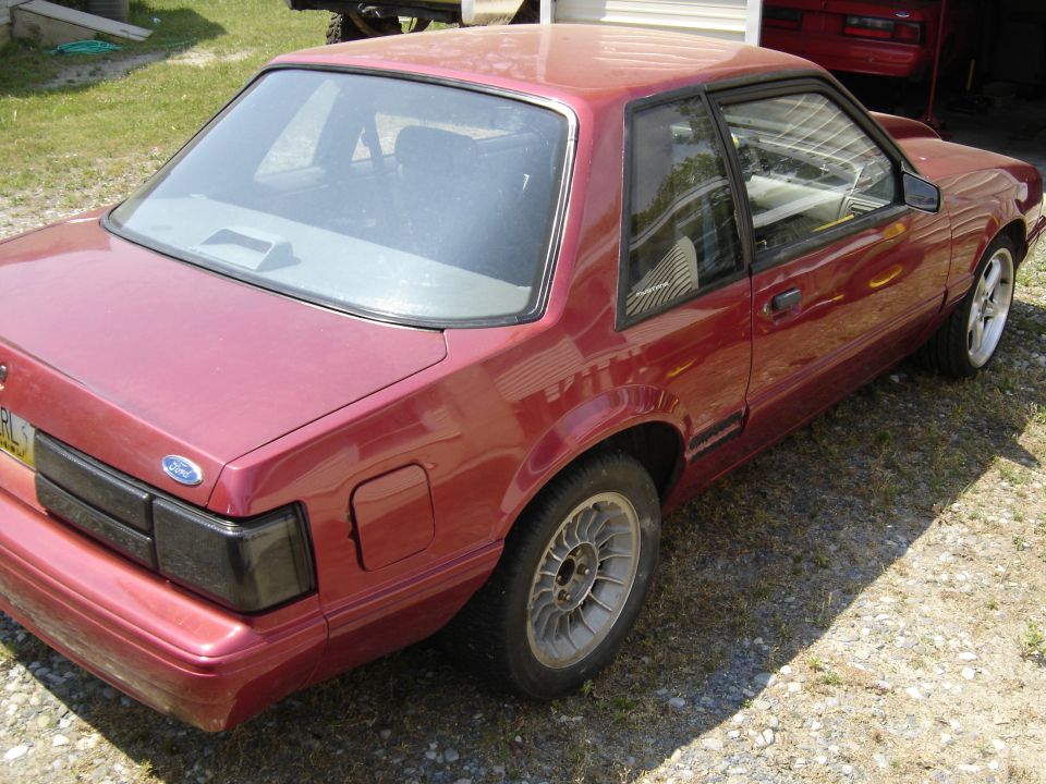 Red Fox-body Mustang notchback from high rear 3/4 with blacked-out taillights and roll bar