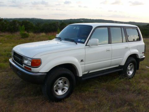 1986 Ford Bronco - This white Toyota Land Cruiser is seen from a 3/4 front angle in a grassy field.