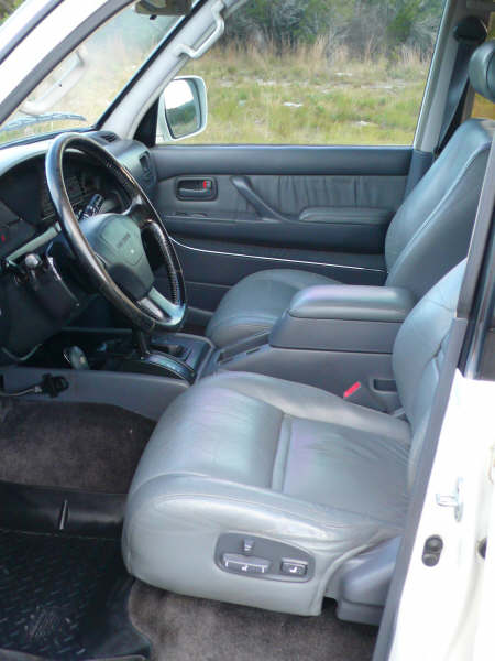 1986 Ford Bronco - The interior of a Toyota Land Cruiser shows the front passenger seat, center console, and dashboard.