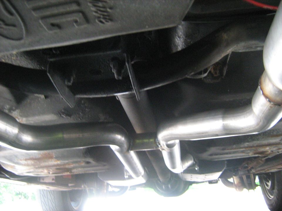 Underside of a car showing dual stainless exhaust crossover pipes