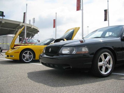 2003 Mercury Marauder - Two cars with hoods open are parked in front of a stadium.