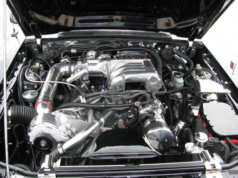 Engine bay with a polished supercharger and intake manifold. Some hoses and wiring are visible