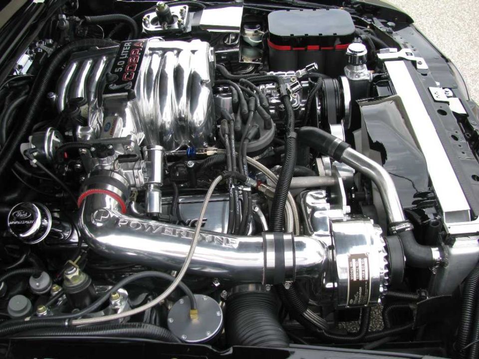 Engine bay with chrome intake manifold labeled 5.0 LITER COBRA and a supercharger