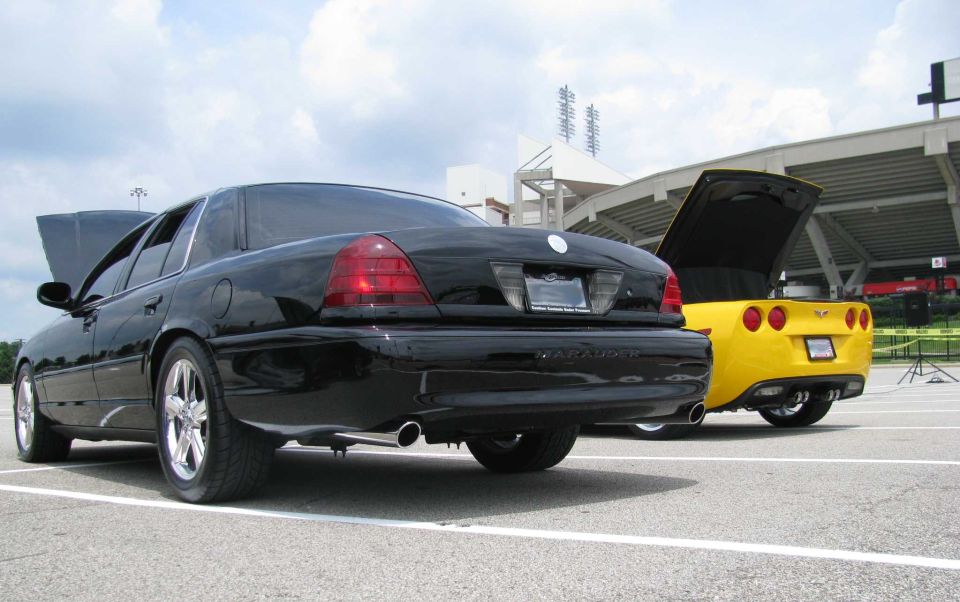 Black 2003 Mercury Marauder parked next to a yellow Chevrolet Corvette, both with hoods open