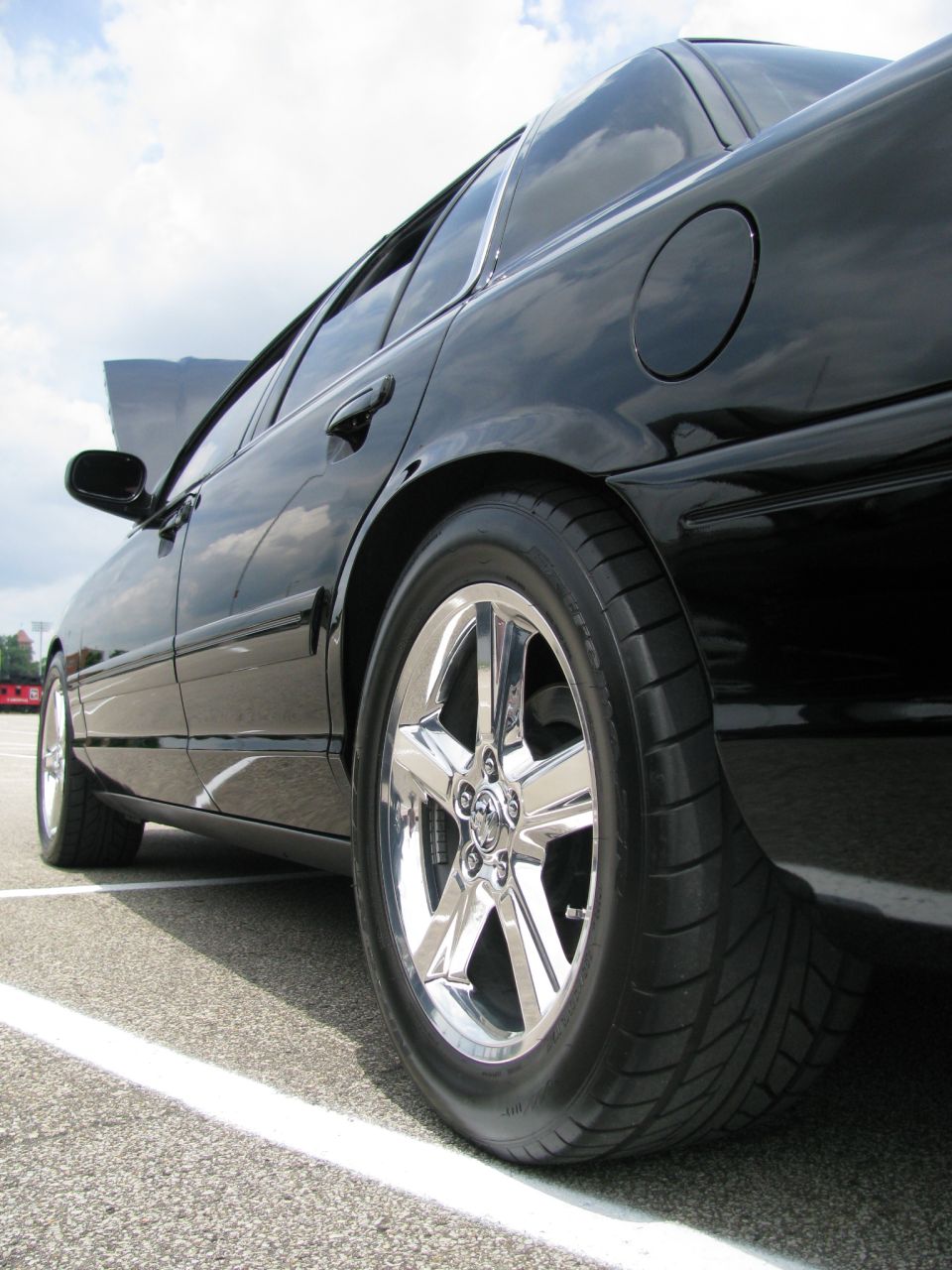 Rear quarter of a black sedan with chrome five-spoke wheels