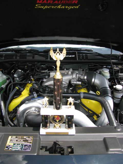 2003 Mercury Marauder - Trophies are displayed in the engine bay of a car, with 'Marauder Supercharged' visible on the hood liner.