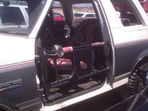 1991 Ford Bronco - The interior of a 1991 Ford Bronco features custom door bars and unique floral seat covers.