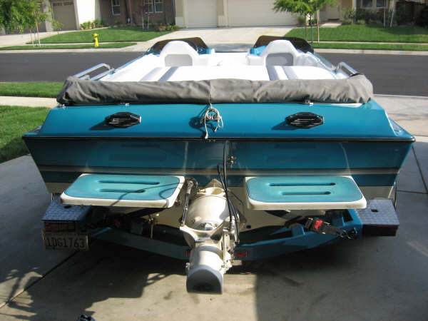 Rear view of teal and white sport boat on trailer in driveway