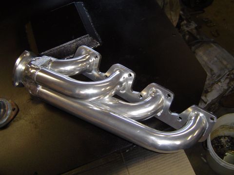 1978 Ford Bronco - A shiny exhaust manifold is shown, likely a replacement part for a vehicle.