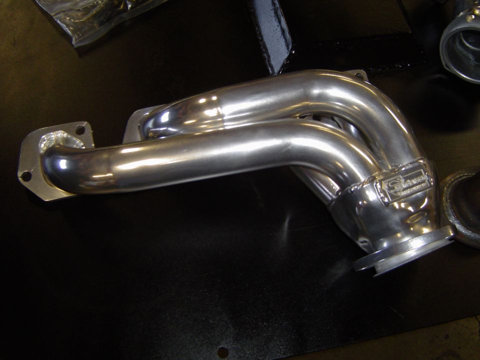 Polished stainless steel exhaust crossover or downpipe on a workbench