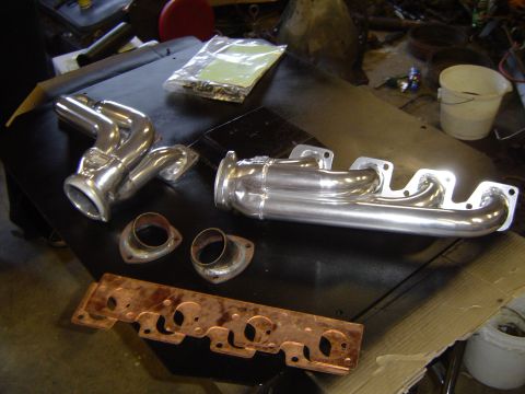 1978 Ford Bronco - Aftermarket exhaust headers and gaskets laid out on a workbench.