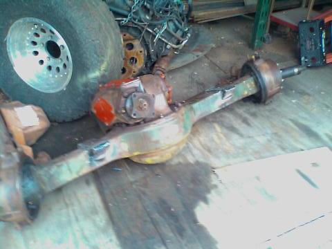 1991 Chevrolet Suburban - A disassembled vehicle rear axle assembly is shown with a large tire and other parts in a workshop setting.