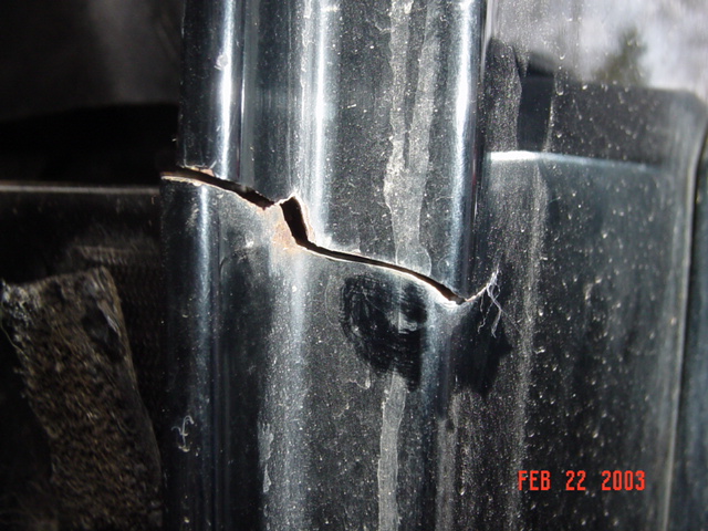 Close-up of split and torn black plastic pillar trim with dents on a vehicle body