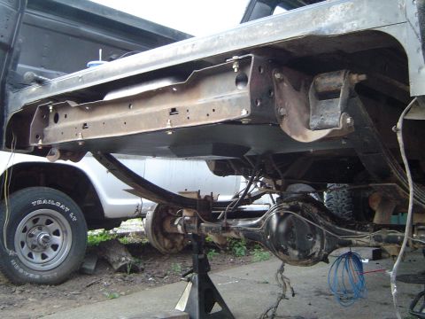 1979 Ford Bronco - The underside of a 1979 Ford Bronco shows its frame and suspension components, with another vehicle partially visible.