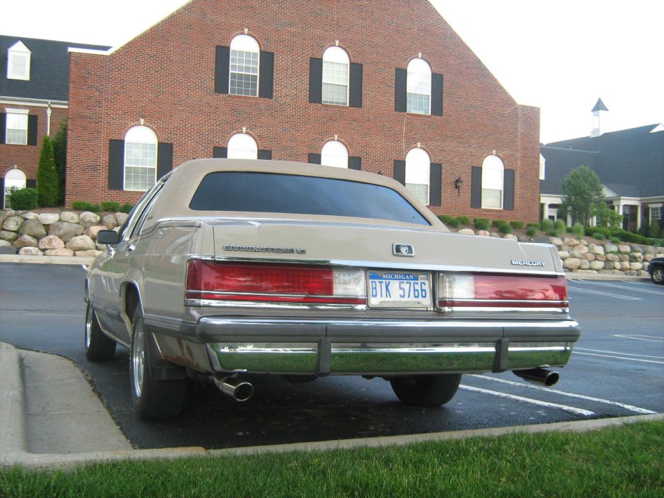 Rear of a tan Mercury Grand Marquis LS in front of a brick building