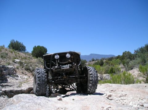 1986 Toyota Hilux - A custom off-road buggy navigates a rocky trail under a clear blue sky.