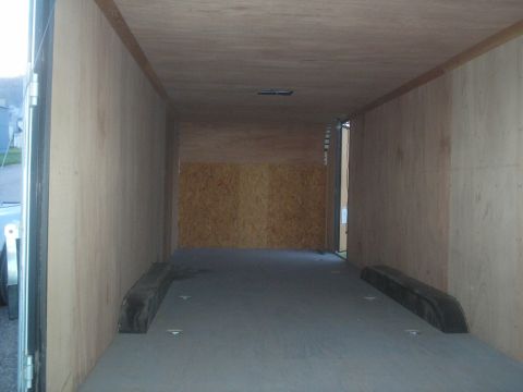 1990 Ford Bronco - The interior of a cargo trailer is shown, empty and with wood paneling on the walls and ceiling.