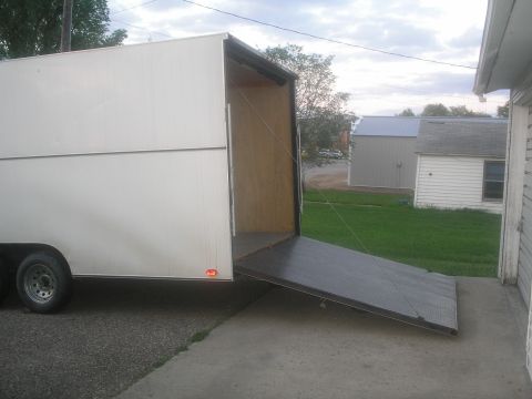 1990 Ford Bronco - A white cargo trailer is parked with its ramp extended, ready for loading or unloading.