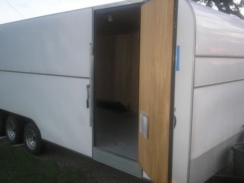 1990 Ford Bronco - The interior of a white cargo trailer is visible through its open side door.