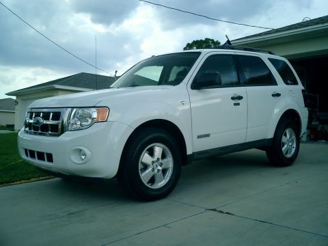 2008 Ford Escape - This white Ford Escape is parked in front of a garage on a cloudy day.