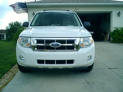 2008 Ford Escape - A white 2008 Ford Escape is parked in front of a garage with an American flag flying.