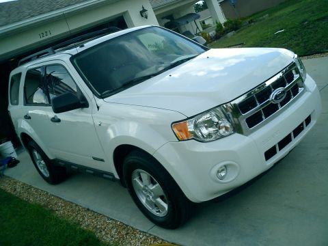 2008 Ford Escape - The front end of a white 2008 Ford Escape is visible, parked in front of a residential garage.