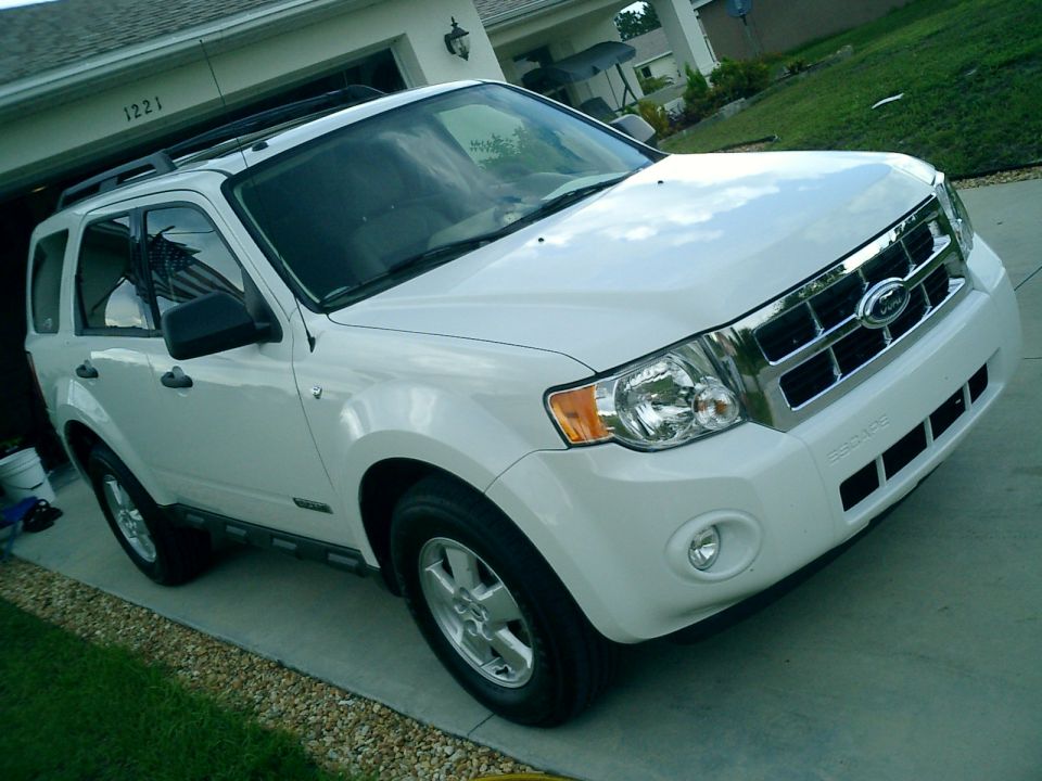 White Ford Escape SUV parked in a driveway in front of a garage