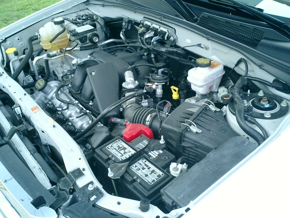 Engine bay of light-duty truck showing intake, battery and brake fluid reservoir