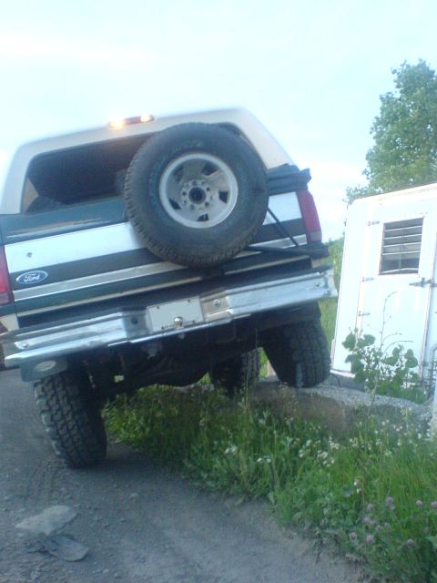 1985 Ford Bronco - This Ford Bronco is positioned on a rock, with its rear facing the camera. A spare tire is visible on the tailgate.
