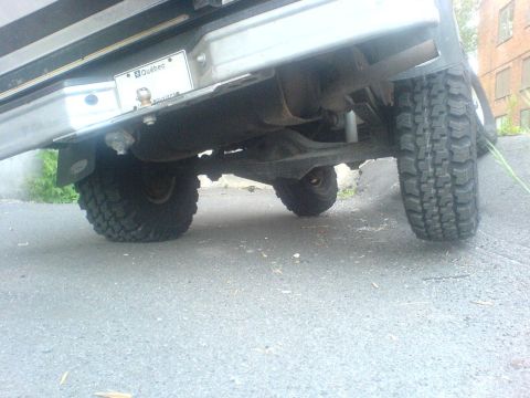 1985 Ford Bronco - The underside of a vehicle, showing its rear axle, tires, and a Quebec license plate.