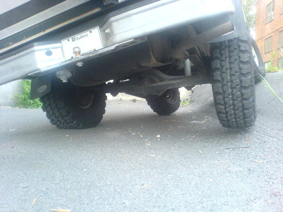 Rear axle and off-road tires of a 1980s SUV, with a Quebec license plate visible